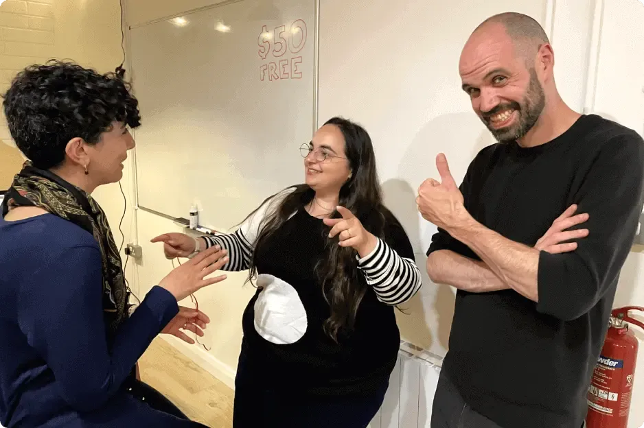 Three of the team laughing together beside a whiteboard in the office