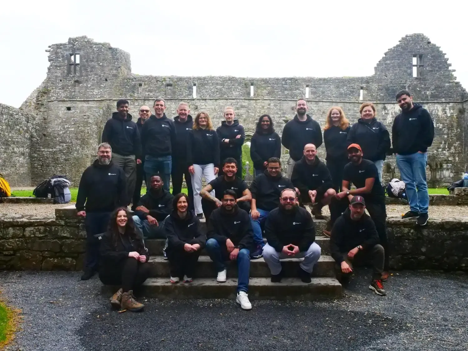 The OnePageCRM team together on the steps of a ruined abbey at a company Gathering in Ireland