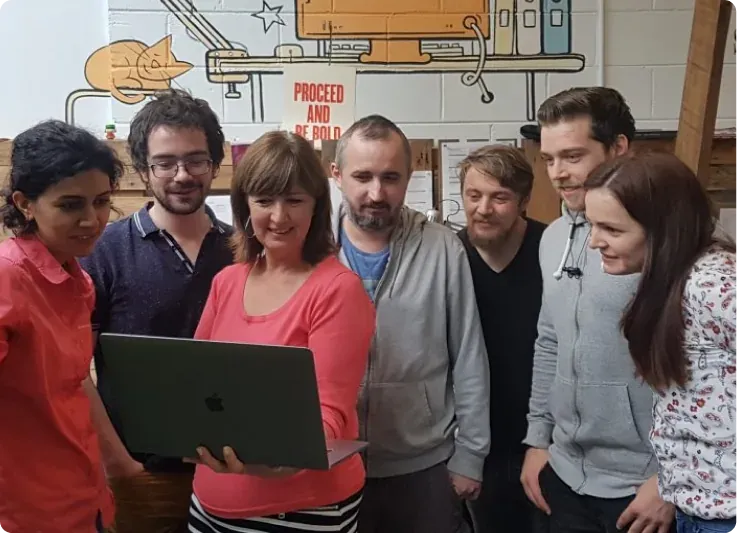 Seven members of the OnePageCRM team crowded around a laptop in the Galway office, under the hand-drawn murals and a PROCEED AND BE BOLD poster